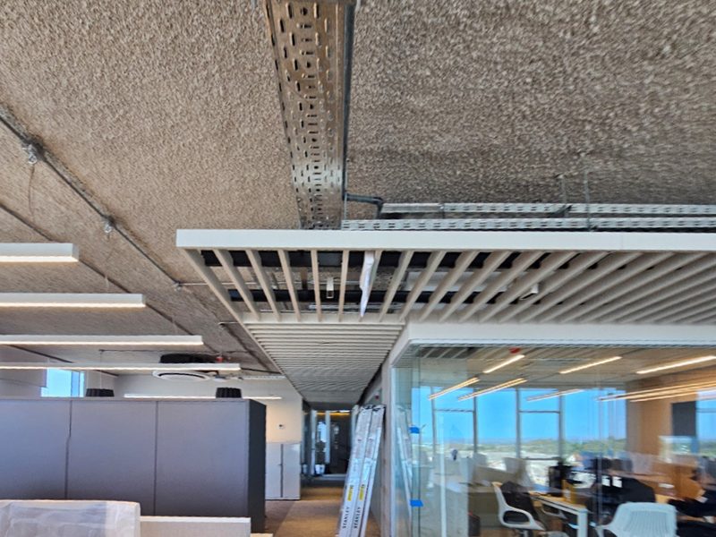 Foto real de las oficinas YPF en construcción, mostrando bandejas eléctricas y cielorrasos terminados